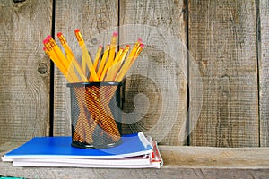 Pencils and writing-books on a wooden shelf.