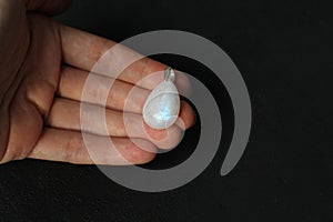 A pendant made of natural stone Moonstone silver lies on a woman`s hand. Author`s jewelry from natural stones. Designer jewelry.