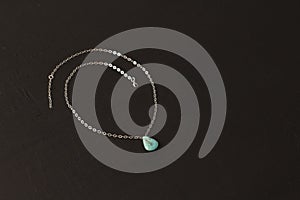 Pendant made of natural turquoise on a silver chain on a black background. Jewelry from natural stones