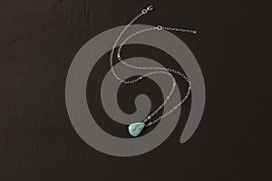 Pendant made of natural turquoise on a silver chain on a black background. Jewelry from natural stones
