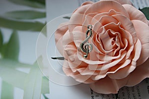 Pendant in the shape of a treble clef on a background of rose flower