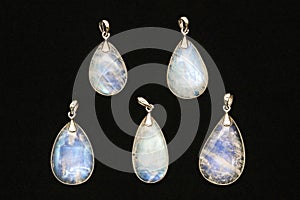 Pendants made of rainbow moonstone behind a black surface