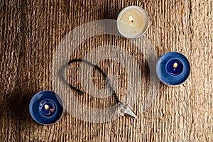 The pendulum on a chain with a natural crystal on a background of wood texture with three burning candles