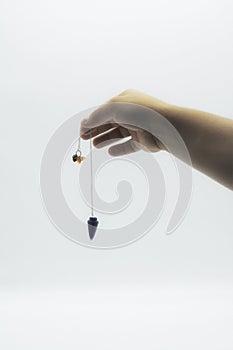 Pendulum dowsing on an isolated white background with an blue crystal and colored chakra stones
