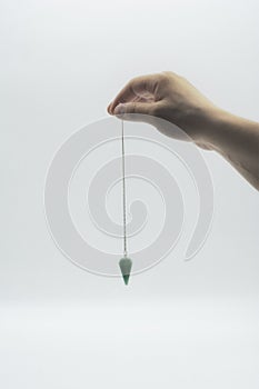 Pendulum dowsing on an isolated white background with a turquoise crystal