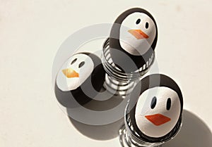Penguin Easter Eggs on metal egg cup white background