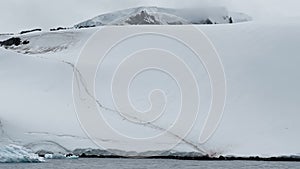 The Penguin Trail in the bay near the Antarctic peninsula, a huge iceberg on mountains, the southern ocean of Antarctica