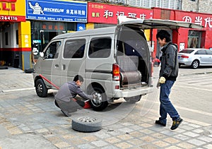 Pengzhou, China: Man Changing Car Tire