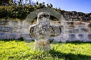 Penitence cross with old medieval abbey wall