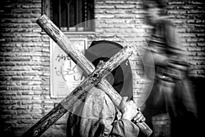 Penitent carrying wooden cross during station of penance in Holy Week