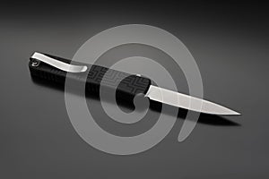 Penknife on a black gradient background. Modern folding knife