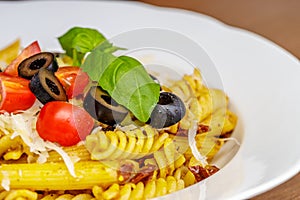 Penne and fusilli pasta with tomatoes, olive, parmesan and basil