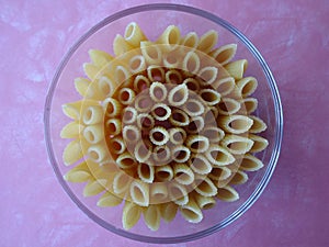 Penne Pasta Arranged in a Glass Dish against a Pink Background