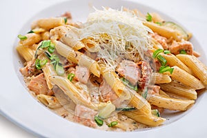 Penne pasta bolognese with parmesan, served on white plate