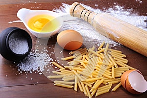 Penne pasta bolognese, spaghetti ready for cooking on the background of egg, flour, salt etc ingredients for pasta