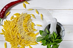 Penne Pasta, green basil, parmesan, sesame, garlic, chilli, eggs lie on a white tree table