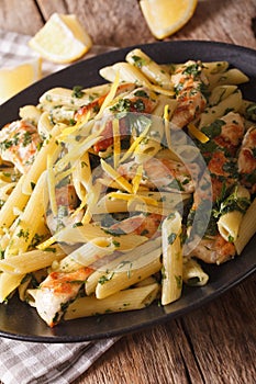 Penne pasta with grilled chicken, greens and lemon sauce close-up. vertical