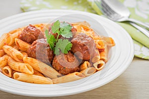 Penne pasta with meatballs in tomato sauce on plate