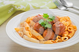 Penne pasta with meatballs in tomato sauce on plate