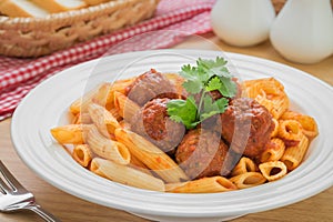 Penne pasta with meatballs in tomato sauce on plate and bread in