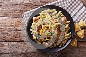 Penne Pasta with pesto, chicken breast and lemon closeup. Horizontal top view