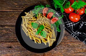 Penne pasta with pesto sauce on a wooden background