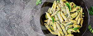 Penne pasta with pesto sauce, zucchini, green peas and basil. I