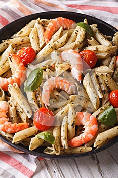 Penne pasta with shrimp, tomato and pesto on a plate closeup. ve