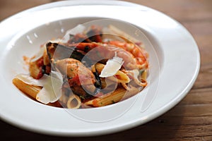 Penne pasta tomato sauce arabiata with seafood on wood background vintage style