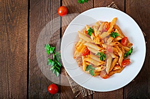 Penne pasta in tomato sauce with chicken, tomatoes decorated with parsley