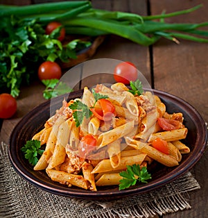 Penne pasta in tomato sauce with chicken, tomatoes decorated with parsley