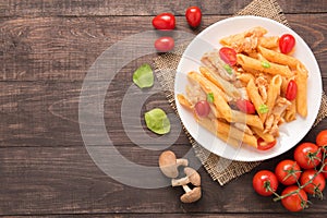 Penne pasta in tomato sauce with chicken on a wooden background