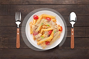 Penne pasta in tomato sauce with chicken on a wooden background