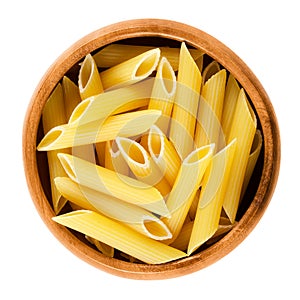 Penne rigate pasta in wooden bowl over white