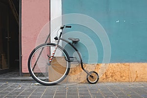 Penny Farthing bicycle, mountain model leaning on a blue wall