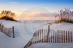 Photo of a sunrise at Pensacola Beach, Florida with beautiful white dunes, sea oats and a dune fence