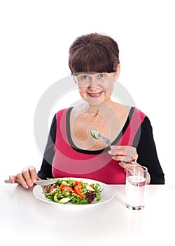 Pension age good looking smiling woman eating green salad