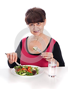 Pension age good looking smiling woman eating green salad