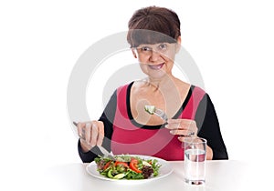 Pension age good looking smiling woman eating green salad