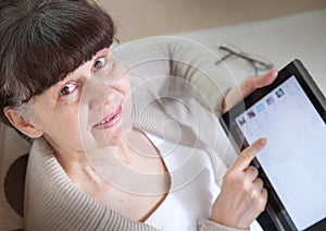 Pension age good looking woman looking internet in tablet device.