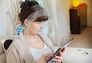 Pension age good looking woman searching in internet on tablet device