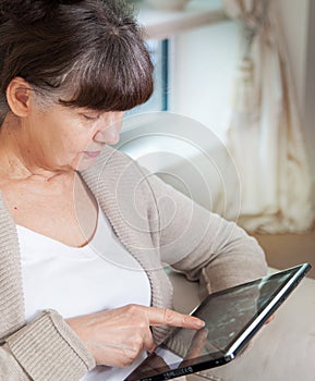 Pension age good looking woman searching in internet on tablet device