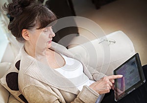 Pension age good looking woman searching in internet on tablet device