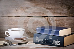 Pension Funds. Stack of books on wooden desk