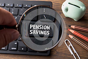 PENSION SAVINGS. Computer keyboard, piggy bank, magnifying glass and office supplies