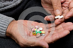 Pensioner holds a lot of colored pills in old hands. Painful old age. Health care of older people