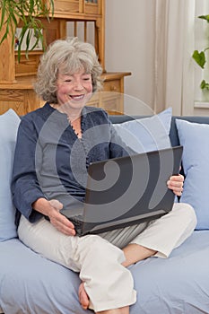Pensioner with laptop on sofa