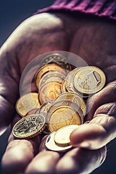 Pensioner man holding in hands euro coins. Theme of low pensions