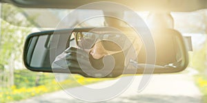 Pensioner in mask reflection in rearview mirror driving car