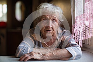 A pensioner old woman sitting at the table in home